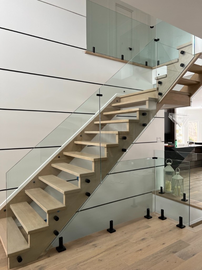 Floating oak staircase with frameless glass railing and black standoffs